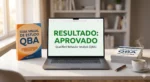 Pacote QBA de preparação para o exame com certificado emoldurado, notebook exibindo resultado aprovado e guia de estudo visual da ABA Practice.